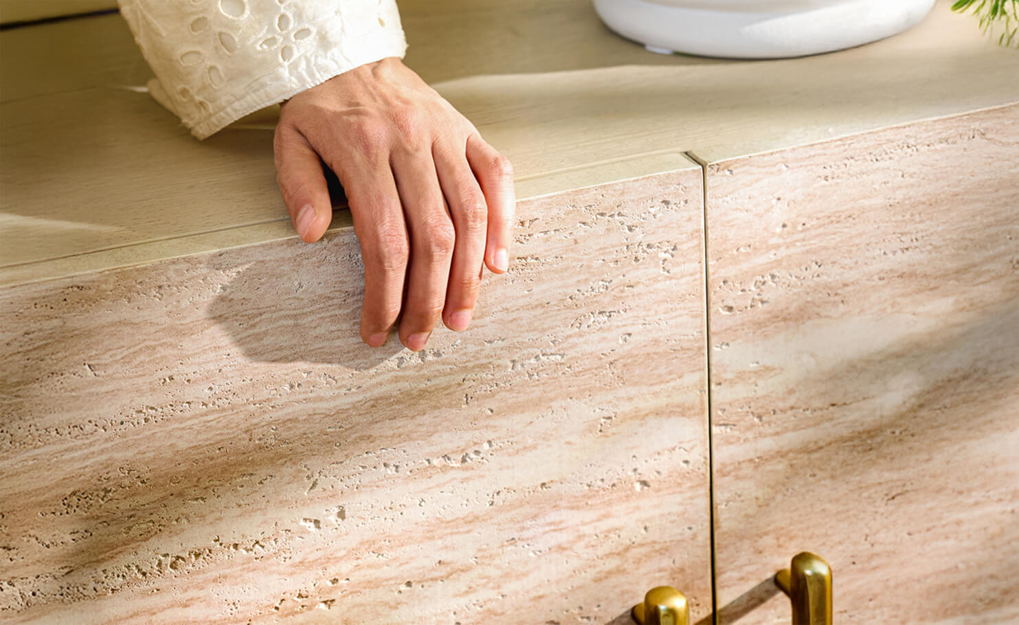 Hand resting on textured cabinet surface with brass hardware